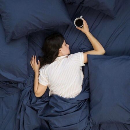 a white woman lying on navy blue comforter