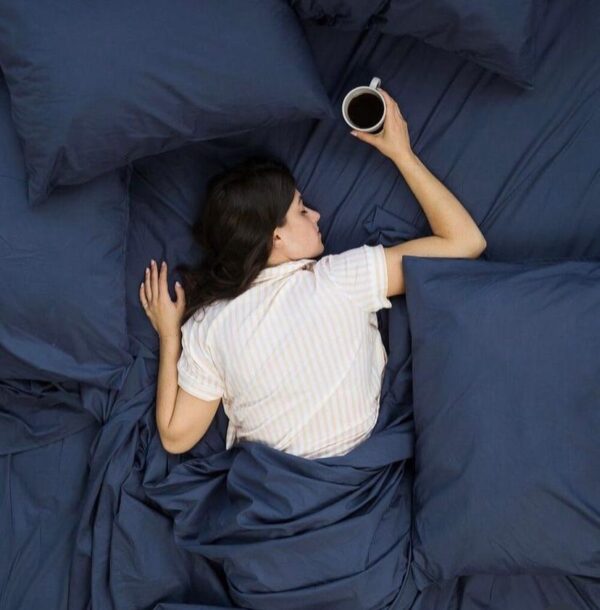 a white woman lying on navy blue comforter