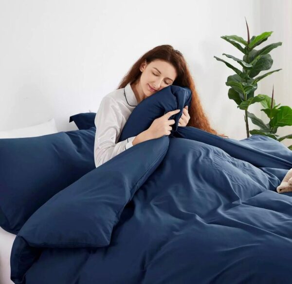 a white woman holding a navy blue comforter